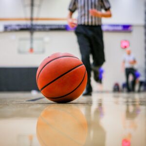 Selective focus shot of a basketball rolling in the hardcourt referee
